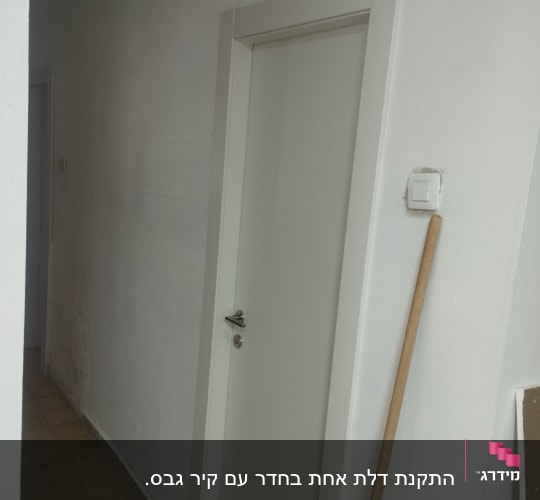 דלת לבנה עם ידית מתכת במסדרון